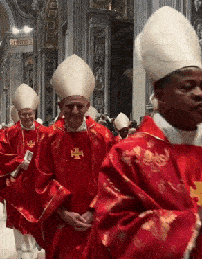 a group of priests are walking in a church and one of them has a cross on his vest