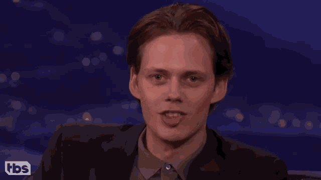 a man in a suit is smiling and sticking his tongue out while sitting on a cbs show
