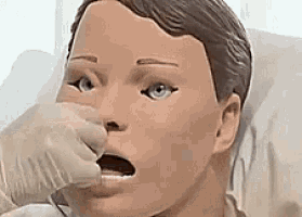 a person is holding a mannequin 's nose while it is laying in a bed .