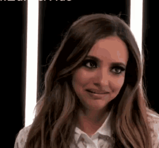 a woman with long brown hair is wearing a white shirt and making a funny face .
