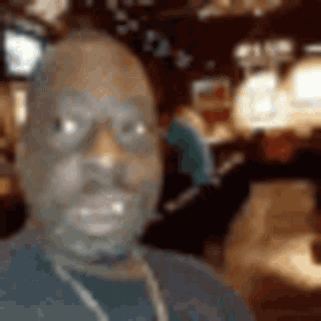 a man wearing glasses and a necklace is taking a selfie .
