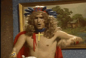 a shirtless man with a cross around his neck is standing in front of a painting