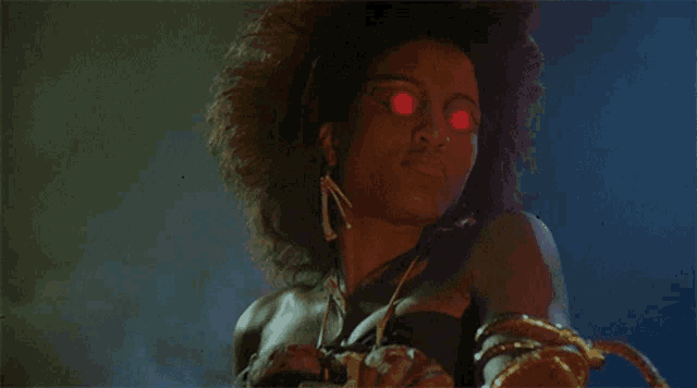 a woman with red eyes and a nose ring looks at the camera