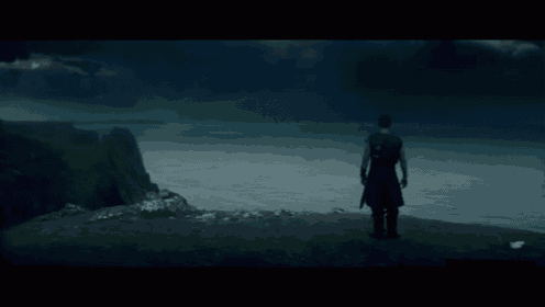a man stands on a hill overlooking the ocean