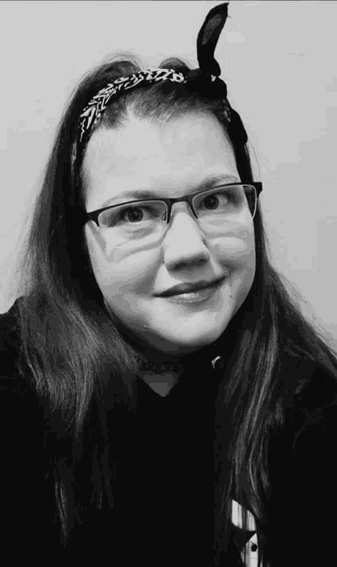 a black and white photo of a girl wearing glasses and a headband with the letter b on it