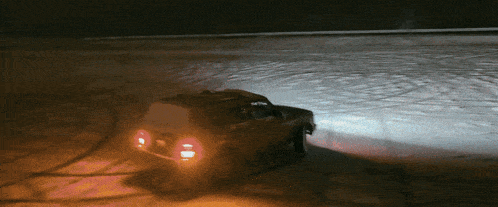 a car is driving down a snowy road at night with its lights on