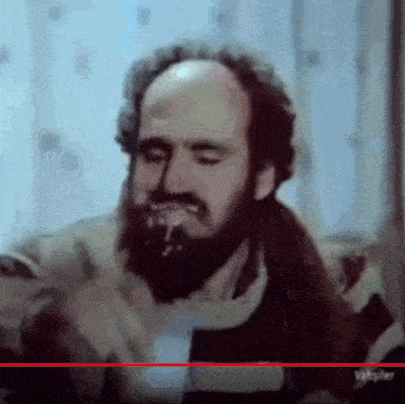 a man with a beard and a bald head is eating something .