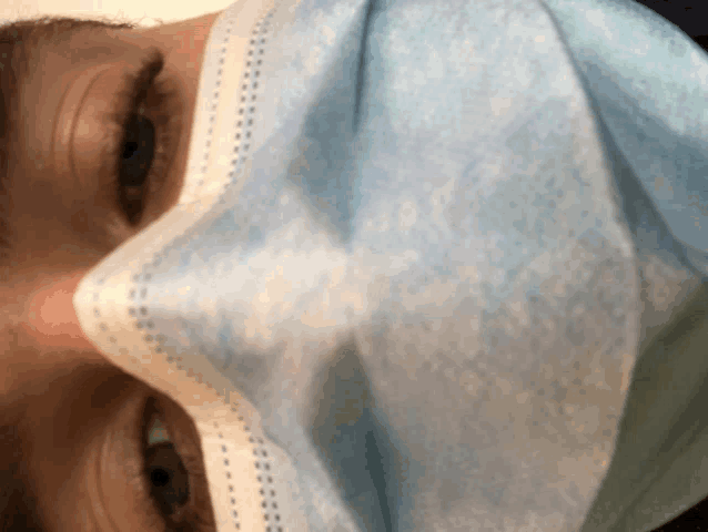 a close up of a person 's face wearing a blue face mask