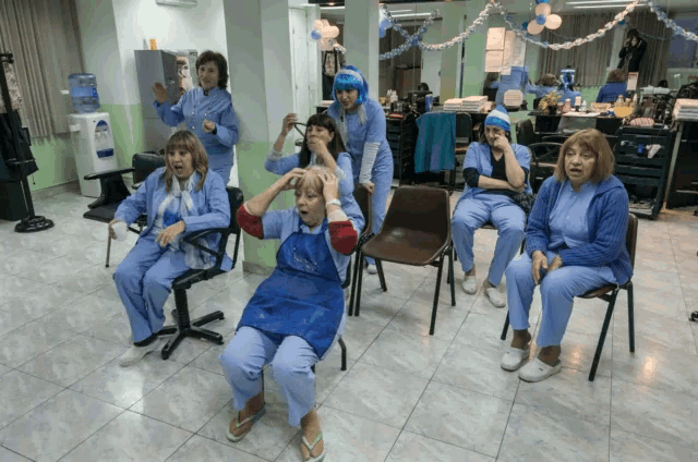 a group of women in blue scrubs sit in chairs