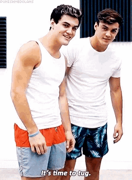 two young men are standing next to each other and one of them is saying `` it 's time to tug . ''