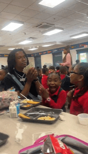 a man is holding a bunch of money in front of a group of kids