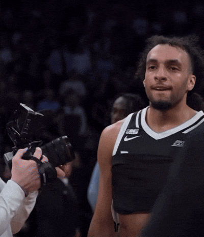 a man taking a picture of a basketball player wearing a black nike jersey
