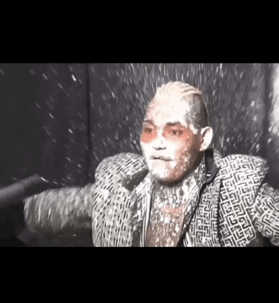 a man with white powder on his face is wearing a greek key jacket
