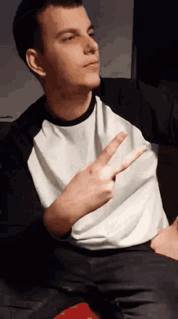 a young man in a white shirt is giving the peace sign
