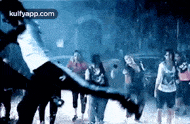 a group of people are standing in a dark room with a person flying in the air .