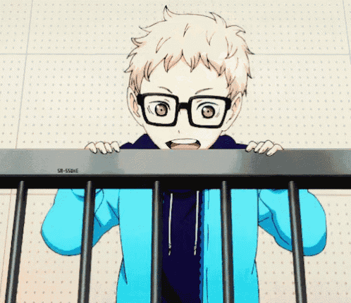 a boy with glasses and a blue jacket is peeking over a railing .