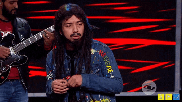 a man with dreadlocks is wearing a jacket that says reggae on the sleeve