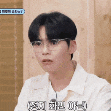 a young man wearing glasses and a white shirt with korean writing on the bottom