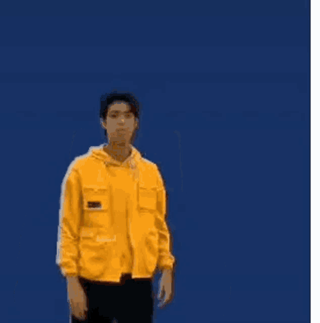 a man in a yellow hoodie is making a surprised face and holding his hands up in front of his face .