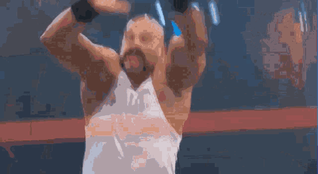 a man in a white tank top is holding a pair of dumbbells with his arms outstretched