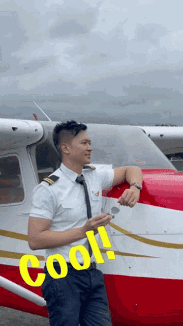 a man leaning against a red and white airplane with the word cool written on his waist