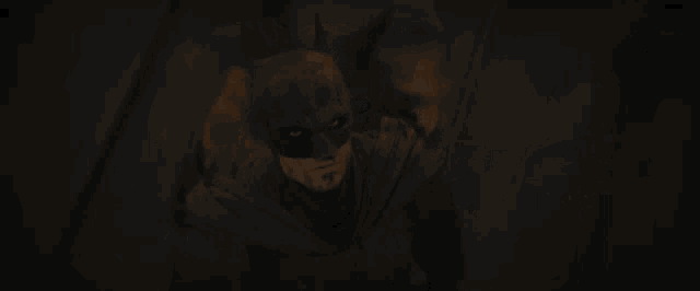 a close up of a man in a batman costume with blood on his face
