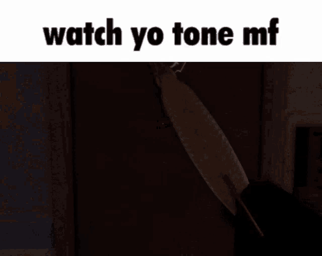 a person holding a knife in a dark room with the words `` watch yo tone mf '' written on it .