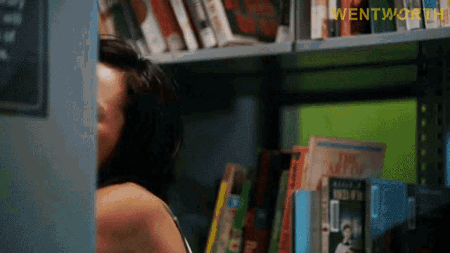 a woman standing in front of a bookshelf with wentworth written on it