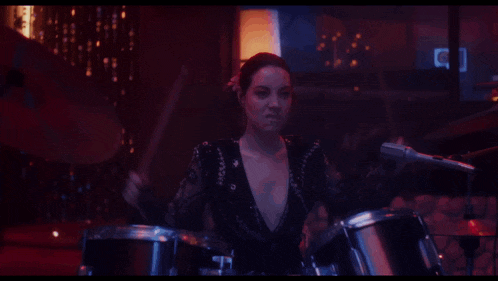 a woman is playing drums in a dark room