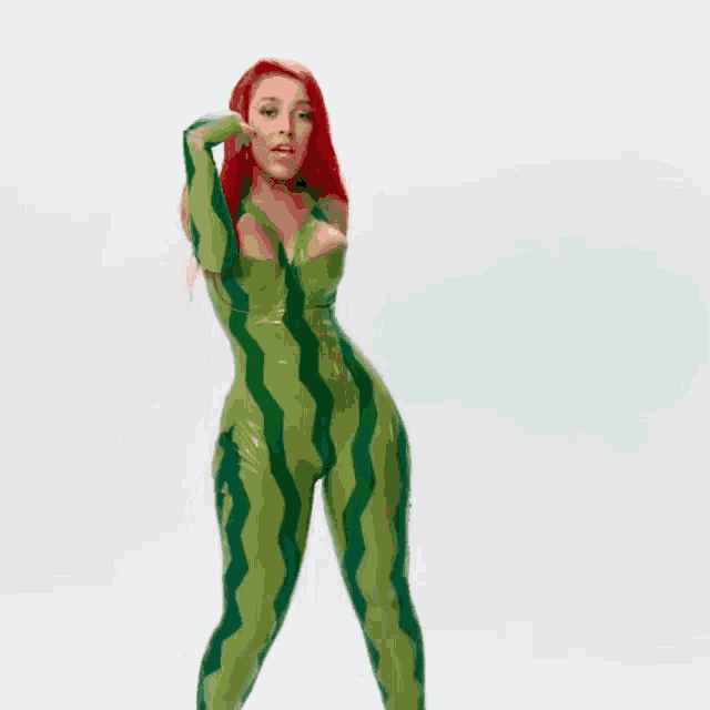 a woman with red hair is wearing a watermelon costume and dancing .