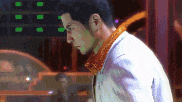 a man with a gold chain around his neck is looking down