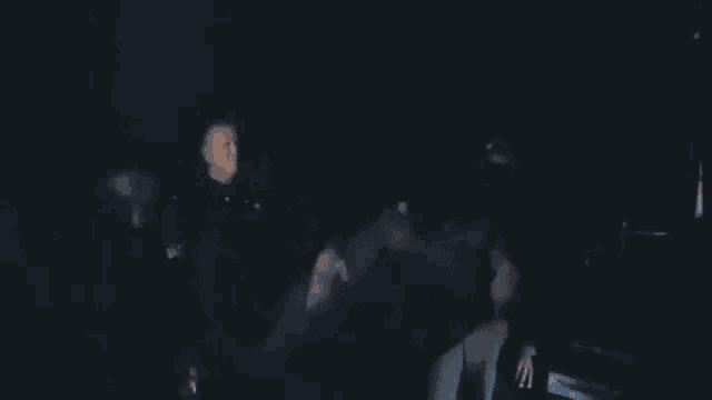 a group of people are hugging each other in a dark room in a dark room .