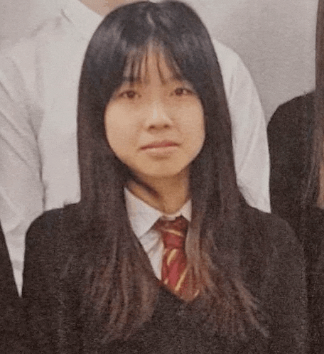 a young girl in a school uniform and tie is posing for a picture with her friends .