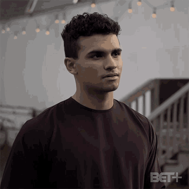 a man wearing a maroon shirt with the bet logo on the bottom