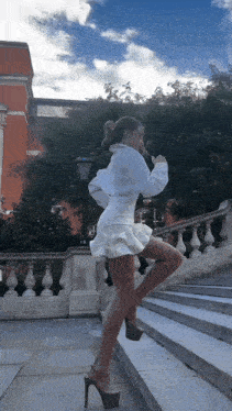 a woman in a white dress is standing on a set of steps