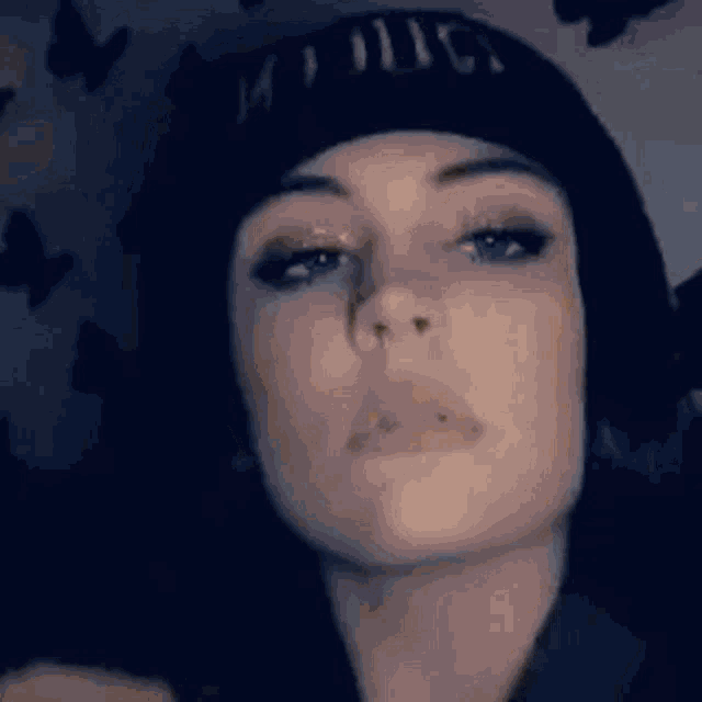 a close up of a woman wearing a black beanie and making a funny face .