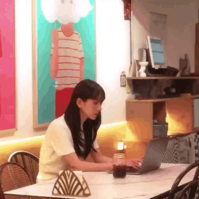 a woman sits at a table with a laptop on it