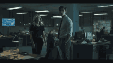a man and a woman are standing in a dark room