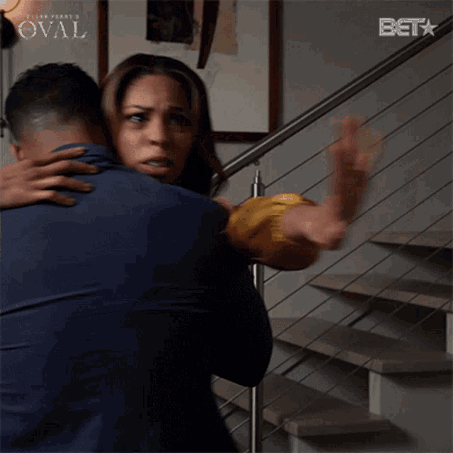 a woman is hugging a man in front of stairs with a bet logo behind them
