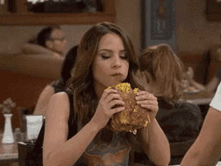 a woman is eating a hamburger at a restaurant .