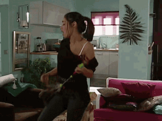 a woman in a black shirt is dancing in a living room