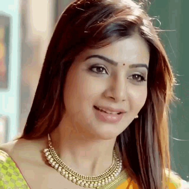 a close up of a woman wearing a pearl necklace and smiling .