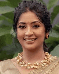 a close up of a woman wearing a necklace and earrings .