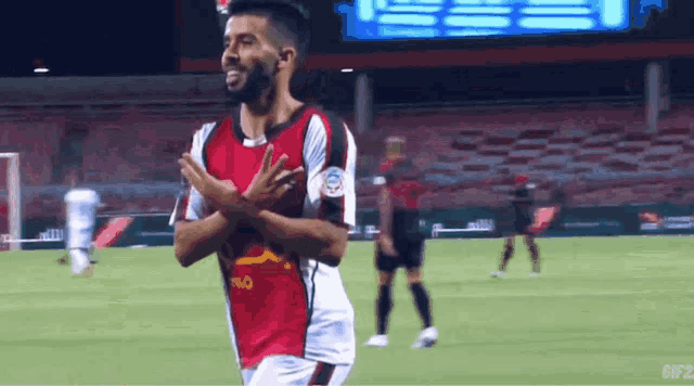 a soccer player wearing a red and black jersey with a yellow logo on it
