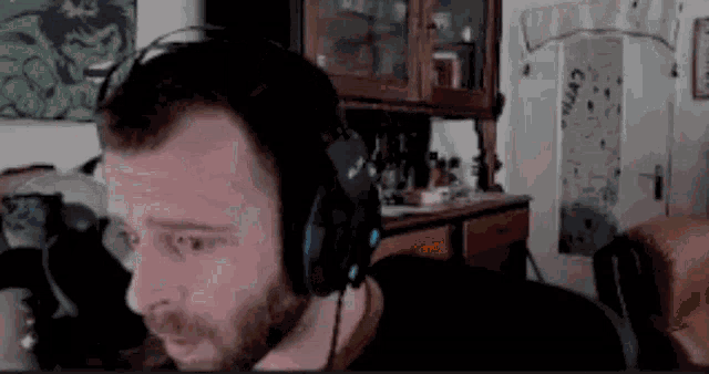 a man with a beard is wearing headphones while sitting in a living room .