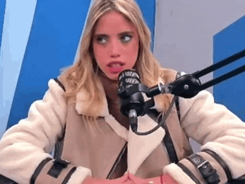 a woman in a white jacket is sitting in front of a microphone .