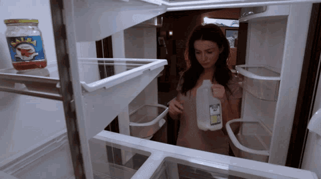 a woman holds a bottle of milk in front of a jar of ketchup