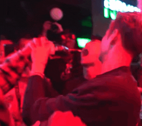 a man in a black shirt is standing in front of a crowd of people with red lights