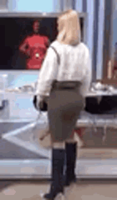 a woman in a white shirt and a green skirt is standing in front of a tv .