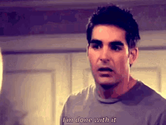 a man in a gray shirt is saying `` i 'm done with it '' while standing in front of a door .
